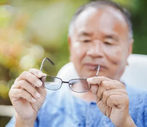 elderly man out of focus staring at his glasses