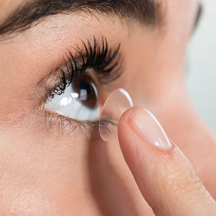 woman putting on contact with dry eye symptoms